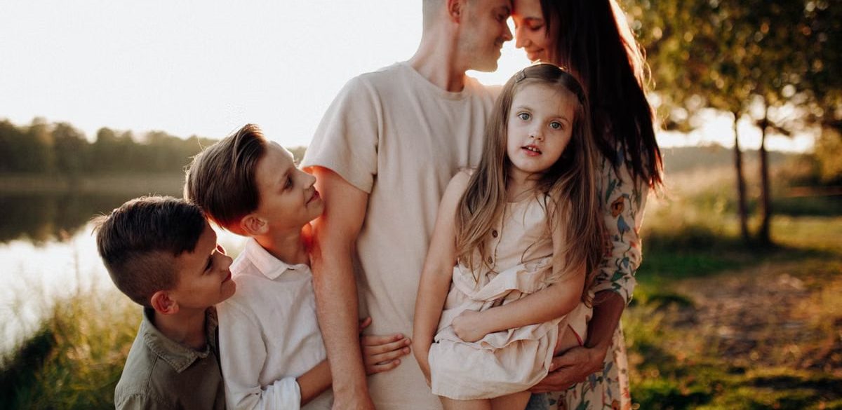 Family enjoying quality time together outdoors by the lake during sunset.