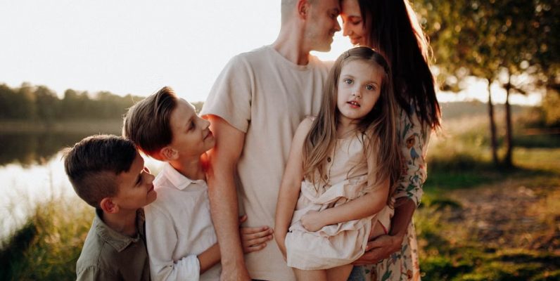Family enjoying quality time together outdoors by the lake during sunset.